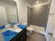 Well-lit bathroom features a shower with gray tiling, toilet, and a vanity with a large mirror and sink at 505 Eastwood St, Durham, NC 27704