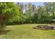 A large backyard with manicured lawn, a firepit, landscaping, and mature trees at 5209 Thistleby Rd, Fuquay Varina, NC 27526