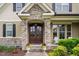Close-up of the front door with stone accents, plants and a glimpse of the covered porch at 5209 Thistleby Rd, Fuquay Varina, NC 27526