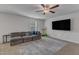 Carpeted living room with a large sectional sofa, mounted flat screen television, and ceiling fan at 536 Gusty Ln, Zebulon, NC 27597
