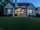 An evening view of the backyard featuring a covered patio with a fireplace, outdoor seating, and manicured lawn at 602 Shelley Rd, Raleigh, NC 27609