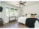 Cozy bedroom featuring hardwood floors, a large window, modern ceiling fan, and stylish decor at 602 Shelley Rd, Raleigh, NC 27609