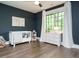 Bedroom featuring hardwood floors, a crib, and a white dresser under a large window at 602 Shelley Rd, Raleigh, NC 27609