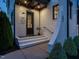 A charming front entrance at dusk with white brick, gray trim, and a well-manicured walkway leading to a black front door at 602 Shelley Rd, Raleigh, NC 27609