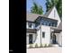 A charming front entrance with white brick, gray trim, and lush landscaping leading to a welcoming black front door at 602 Shelley Rd, Raleigh, NC 27609