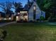 A charming two-story home with white brick, gray trim, and a large, well-maintained front lawn at dusk at 602 Shelley Rd, Raleigh, NC 27609