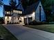 A stunning white brick home with gray trim, a two-car garage, and a well-manicured front yard at dusk at 602 Shelley Rd, Raleigh, NC 27609