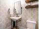 Charming powder room with patterned wallpaper, decorative mirror and a floating vanity with stylish fixtures at 602 Shelley Rd, Raleigh, NC 27609