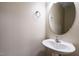 A half bathroom featuring a stylish round mirror and a pedestal sink at 7229 Terregles Dr, Raleigh, NC 27617