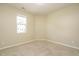 A bedroom featuring beige walls, carpeted floors, and a window at 7229 Terregles Dr, Raleigh, NC 27617