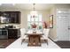 Open-concept dining room with hardwood floors, shutters, modern light fixture, and adjacent kitchen at 7229 Terregles Dr, Raleigh, NC 27617