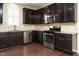 A modern kitchen featuring stainless steel appliances, granite countertops, dark cabinetry, and hardwood floors at 7229 Terregles Dr, Raleigh, NC 27617
