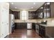 An open kitchen with dark cabinets, stainless steel appliances, granite countertops, and hardwood floors at 7229 Terregles Dr, Raleigh, NC 27617