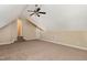 A spacious attic room features neutral walls, carpeting, a ceiling fan, and steps leading to another room at 7940 Milltrace Run, Raleigh, NC 27615