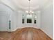 Elegant dining room featuring a tray ceiling, chandelier, bay windows, and hardwood floors at 7940 Milltrace Run, Raleigh, NC 27615