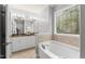 Bathroom features soaking tub, decorative window, and white cabinets at 84 N Hadrian Ct, Clayton, NC 27520
