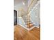 Inviting foyer with hardwood floors and staircase featuring wooden handrail and white balusters at 8401 Hobhouse Cir, Raleigh, NC 27615