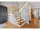 Inviting foyer with hardwood floors and staircase featuring wooden handrail and white balusters at 8401 Hobhouse Cir, Raleigh, NC 27615