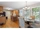 Eat-in kitchen with hardwood floors, light wood cabinetry, a chandelier, and natural light from the windows at 8401 Hobhouse Cir, Raleigh, NC 27615