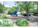 Community playground with a blue play structure, mature trees, flowers and walkway at 101 Lakeshore Dr. Dr, Durham, NC 27713