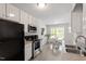 Well-lit kitchen featuring white cabinetry, stainless steel appliances, and a view to the dining nook at 1021 S Fieldhaven Dr, Fuquay Varina, NC 27526