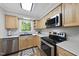 Bright kitchen featuring wood cabinets, stainless steel appliances, and a window offering a view of the trees at 104 Farnham Ct, Garner, NC 27529