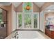Luxurious bathroom featuring a soaking tub with a large window overlooking a serene, wooded view at 108 Martinique Pl, Cary, NC 27511
