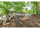 Expansive backyard featuring mature trees, a greenhouse, screened porch and vibrant outdoor seating area at 1107 Daleland Dr, Raleigh, NC 27612