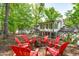 Backyard with a fire pit and red Adirondack chairs under a canopy of mature trees, perfect for outdoor gatherings at 1107 Daleland Dr, Raleigh, NC 27612