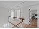 Upstairs hallway with hardwood floors, white railing, and open access to multiple rooms at 1107 Daleland Dr, Raleigh, NC 27612