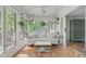 Inviting sunroom filled with natural light, featuring a comfortable sofa and hanging plants at 1107 Daleland Dr, Raleigh, NC 27612