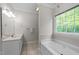 Bright bathroom with a soaking tub under a large window and a vanity with sink and mirror at 1245 Torchlight Way, Raleigh, NC 27603