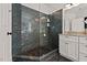 Modern bathroom boasts glass-enclosed shower, dark tiling, pebble floor, and granite-topped vanity at 1427 Bungalow Ave, Durham, NC 27703