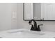Close-up of bathroom sink with a black faucet, white countertop, and black-framed mirror at 1513 Fairfax Rd, Durham, NC 27701