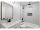 Modern bathroom with white tiles, a shower-over-tub, a vanity with a sleek mirror and black hardware at 1513 Fairfax Rd, Durham, NC 27701