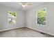 Bedroom with two windows offering natural light, featuring light wood floors, ceiling fan, and neutral paint at 1513 Fairfax Rd, Durham, NC 27701
