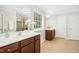 Bathroom featuring dual sinks with wood cabinets, tiled floors, and large mirror at 1557 Tice Hurst Ln, Apex, NC 27502