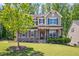 Inviting two-story home featuring a landscaped front yard and a charming covered porch with stone accents at 1557 Tice Hurst Ln, Apex, NC 27502
