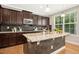 Spacious kitchen features granite countertops, dark wood cabinets, a large island, and stainless steel appliances at 1557 Tice Hurst Ln, Apex, NC 27502