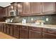 Chef's kitchen features dark wood cabinets, granite countertops, stainless steel appliances, and gas range at 1557 Tice Hurst Ln, Apex, NC 27502