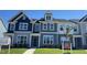 Modern townhome with a striking blue and gray exterior, complemented by lush green grass and professional landscaping at 1565 Wendell Valley Blvd, Wendell, NC 27591