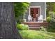 Inviting back porch with a red French door, white Adirondack chairs, and lush landscaping, perfect for relaxation at 1603 Hermitage Ct, Durham, NC 27707
