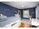 Stylish bedroom with blue walls, light hardwood floors, a desk area and custom bed with storage at 1603 Hermitage Ct, Durham, NC 27707