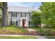 Beautiful gray two-story home with a red front door, black shutters and brick walkway at 1603 Hermitage Ct, Durham, NC 27707