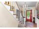 Bright foyer featuring a chandelier, staircase, and open red front door at 1603 Hermitage Ct, Durham, NC 27707