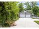 Close up view of two-car garage with white doors and concrete driveway, surrounded by greenery at 1603 Hermitage Ct, Durham, NC 27707