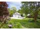 View of the two-car garage with white doors surrounded by a large lawn and garden with decorative plants and a bird bath at 1603 Hermitage Ct, Durham, NC 27707