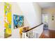 Bright hallway featuring a staircase with colorful wall art and hardwood flooring at 1603 Hermitage Ct, Durham, NC 27707