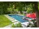 Lush landscaping surrounding backyard swimming pool and hot tub with an umbrella at 1603 Hermitage Ct, Durham, NC 27707