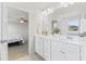 Bright bathroom with double vanity sinks, white cabinetry, and a view into the bedroom at 176 Belleforte Park Cir, Garner, NC 27529